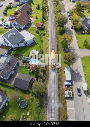 Il treno giallo corre su binari ferroviari attraverso il villaggio, circondato da case e giardini, macchina per compattazione, Hermann Hessebahn, Althengstett, Black for Foto Stock