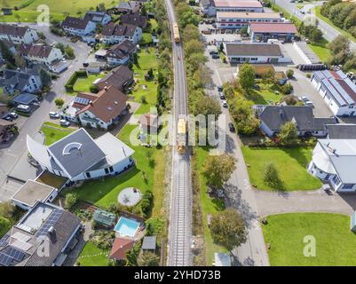 Il treno giallo attraversa il villaggio su rotaie, circondato da case e giardini verdi, macchina per compattazione, Hermann Hessebahn, Althengstett, Black Fo Foto Stock