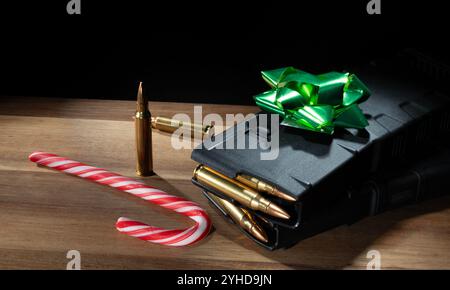 Il regalo di Natale ideale per un proprietario di armi, con due caricatori di fucili d'assalto caricati, una canna da zucchero, cartucce di ricambio e un fiocco verde sulla parte superiore. Foto Stock