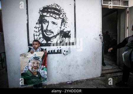 Nablus, Palestina. 11 novembre 2024. Un bambino di scuola palestinese sventola una bandiera palestinese e tiene un ritratto del defunto presidente palestinese Yasser Arafat, presidente dell'Autorità palestinese, nel ventesimo anniversario della sua morte durante una manifestazione alla Salem School a est della città di Nablus in Cisgiordania. Arafat morì nel 2004 all'ospedale militare Percy di Parigi all'età di 75 anni. Credito: SOPA Images Limited/Alamy Live News Foto Stock