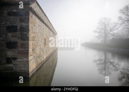 HAMPTON, Virginia - lo storico fossato e le fortificazioni esterne di Fort Monroe, il più grande forte in pietra d'America, emergono attraverso la nebbia mattutina. L'atmosfera Foto Stock