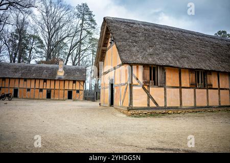 JAMESTOWN, Virginia - il ricostruito James Fort presso l'insediamento di Jamestown presenta caratteristici edifici di wattle e daub di colore arancione disposti lungo sentieri sterrati. La struttura del forte mostra la tipica architettura coloniale inglese dei primi anni del XVII secolo e la pianificazione degli insediamenti. La disposizione dell'edificio riflette le considerazioni difensive e pratiche del forte originale all'interno delle sue pareti triangolari della palizzata. Foto Stock