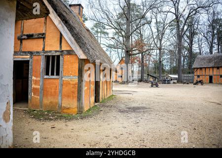 JAMESTOWN, Virginia - il ricostruito James Fort presso l'insediamento di Jamestown presenta caratteristici edifici di wattle e daub di colore arancione disposti lungo sentieri sterrati. La struttura del forte mostra la tipica architettura coloniale inglese dei primi anni del XVII secolo e la pianificazione degli insediamenti. La disposizione dell'edificio riflette le considerazioni difensive e pratiche del forte originale all'interno delle sue pareti triangolari della palizzata. Foto Stock