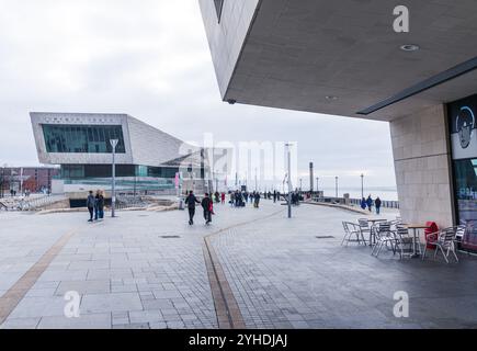 Persone che camminano accanto al Mersey Ferry Building e al Museum of Liverpool, sul lungomare storico nel centro di Liverpool, in una giornata nuvolosa. Foto Stock