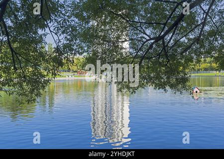 Riflesso di un edificio residenziale a più piani sulla superficie dell'acqua. Stagno nel distretto sud-ovest di Mosca (via Vvedensky), Russia. Soleggiato da Foto Stock