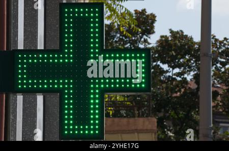 Croce a LED bifacciale pubblicitaria per l'uso esterno e interno da parte di farmacie e altre strutture mediche, emettendo una luce verde brillante Foto Stock