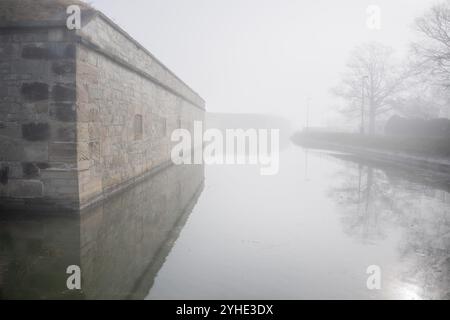 HAMPTON, Virginia - lo storico fossato e le fortificazioni esterne di Fort Monroe, il più grande forte in pietra d'America, emergono attraverso la nebbia mattutina. L'atmosfera Foto Stock