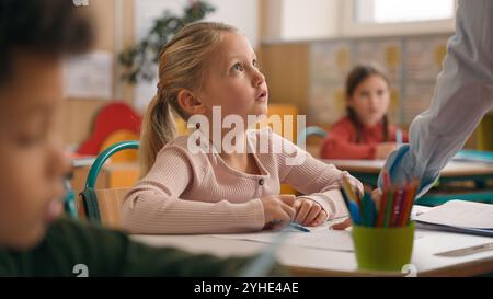 Insegnante di donna caucasica nella scuola elementare insegnare ai bambini di classe compito di scrivere in classe conoscenza studiare istruzione primaria lezione femminile Foto Stock