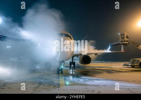 Sbrinamento del velivolo prima del volo. Durante le nevicate invernali, servizio notturno e a terra all'aeroporto. Foto Stock