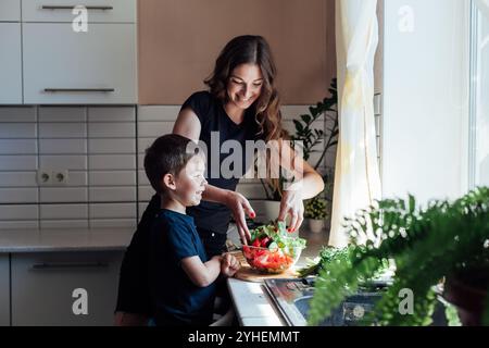 Mamma e figlio preparano l'insalata per il cibo in cucina Foto Stock