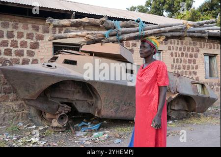 SUDAN DEL SUD, Stato dei Laghi, Rumbek, caserma abbandonata dell'esercito sudanese, vecchio carro ammuffito dalla guerra tra SPLA e esercito sudanese, donna portare legni da fuoco / SÜDSUDAN, Stato dei Laghi, Stadt Rumbek, alte Kaserne und alter Schützenpanzer der nordsudanesischen Armee aus dem Krieg mit der SPLA Sudanesische Volksbefreiungsarmee, Frau trägt Feuerholz Foto Stock