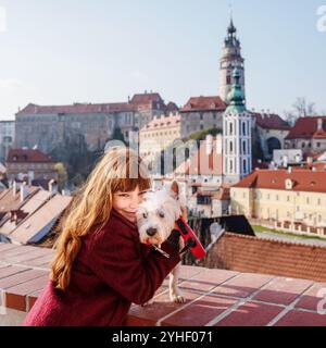 Ragazza che abbraccia il cane terrier orientale sullo sfondo di Cesky Krumlov Foto Stock