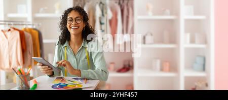 Stilista creativo al lavoro in uno studio elegante pieno di tessuti Foto Stock