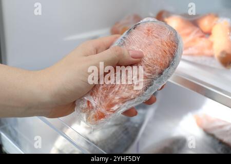 Donna che prende una bistecca di salmone congelata dal frigo, primo piano Foto Stock