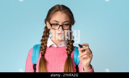 Ragazza adolescente con i pigtail e gli occhiali scrive con marcatore sullo schermo Foto Stock