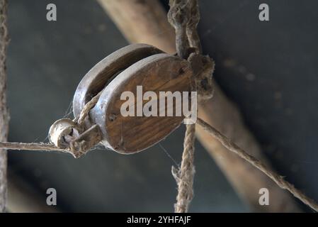 Artigianato vintage: Sistema di pulegge in legno antico appeso in capanna in legno rustico Foto Stock