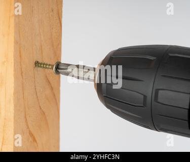 Primo piano di una vite che entra in una scheda sotto il cacciavite. Foto Stock