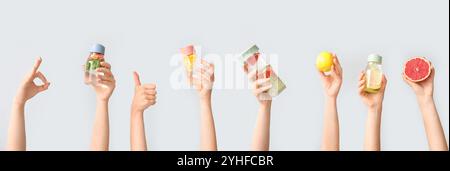 Set di mani che reggono acqua infuso diversa su sfondo chiaro Foto Stock