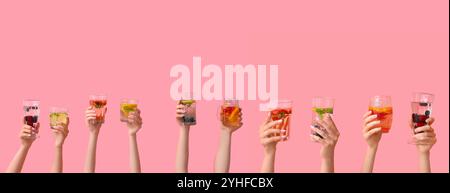 Set di mani che reggono acqua infuso diversa su sfondo rosa Foto Stock