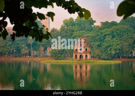 La Turtle Tower presso il lago Hoan Kiem ad Hanoi, Vietnam, è stata catturata durante un momento tranquillo con la luce del mattino che si riflette sull'acqua. Foto Stock