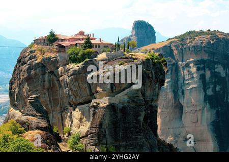 Il monastero mozzafiato di Meteora, arroccato in cima a massicce formazioni rocciose, una meraviglia architettonica che si fonde armoniosamente con l'aspro paesaggio greco Foto Stock