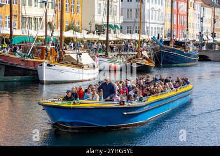 Copenhagen, persone in un tour in barca dei canali lungo il canale Nyhavn, oltre le case colorate del XVII secolo e i ristoranti in questa zona, Danimarca, 2024 Foto Stock