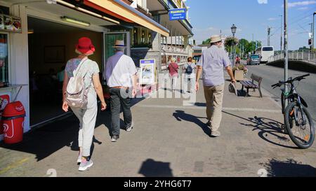 Donna con cappello rosso che cammina lungo la passeggiata sul Reno nella famosa città turistica di Rudesheim in Germania. Foto Stock