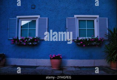 Golling an der Salzach, Austria - 14 giugno 2021: Due finestre con persiane e fiori in fioriere a Golling e der Salzach, Austria. Foto Stock