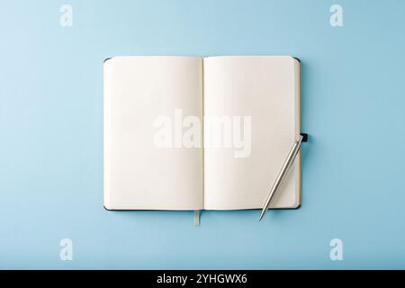 Vista dall'alto del notebook e della penna a sfera su sfondo blu Foto Stock