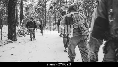 Soldato di fanteria americano, è difficile attraversare Forest Road nel freddo inverno. Squadra militare USA Marching by Country Road. Soldati dell'esercito degli Stati Uniti d'America del mondo Foto Stock