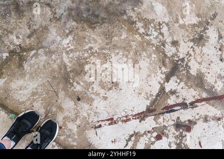 Pavimento in calcestruzzo con stampe di scarpe e macchie in un ambiente industriale durante il giorno Foto Stock