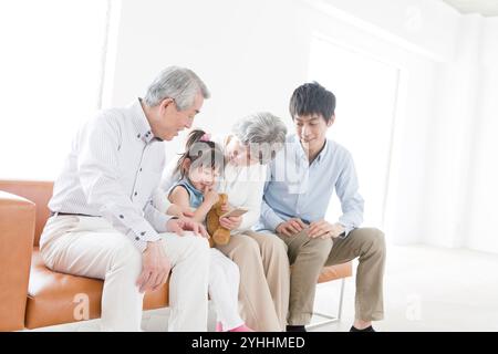 Nonno, nonna, figlio e due nipoti seduti sul divano Foto Stock