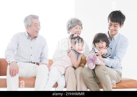 Nonno, nonna, figlio e due nipoti seduti sul divano Foto Stock