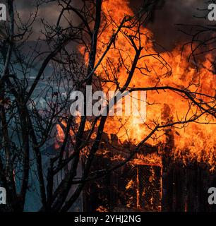 Fuoco nella vecchia casa di legno. Casa in fiamme. Pienamente coinvolto. Foto di un'enorme fiamma che distrae la casa in fiamme. Concetto di sicurezza antincendio. Casa distrutta da Foto Stock