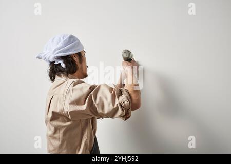 Uomo che utilizza un avvitatore a percussione Foto Stock