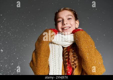 Una ragazza allegra celebra l'inverno con un grande sorriso, vestito con abiti caldi e accoglienti. Foto Stock