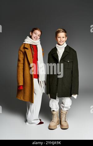 Due bambini indossano abiti e giacche oversize comodi per un'allegra moda invernale. Foto Stock