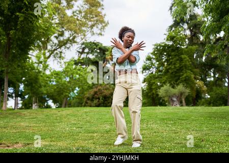 Una donna africana con i capelli ricci, indossa una giacca in denim, balla e si diverte, irradiando gioia ed energia nei suoi movimenti. Foto Stock