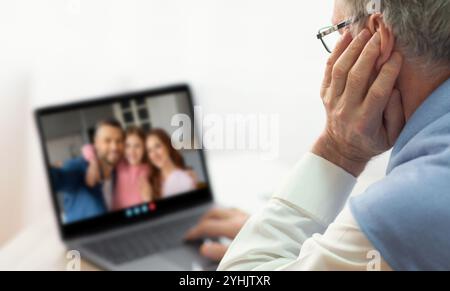 Uomo anziano impegnato in una riunione virtuale di famiglia su un portatile a casa Foto Stock