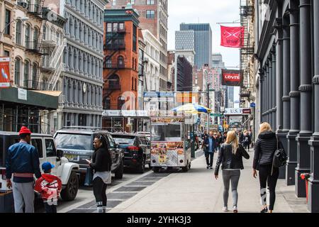 New York City, USA - 15 aprile 2017: Vivace scena di strada con pedoni, veicoli e un carrello alimentare nel quartiere di SoHo. Foto Stock