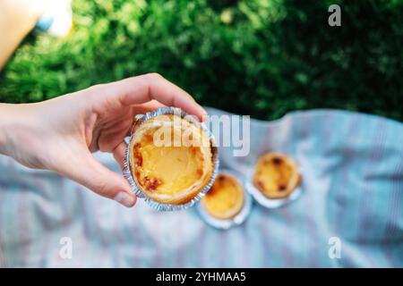 Pasticceria tradizionale portoghese pastel de nata in mano donna Foto Stock