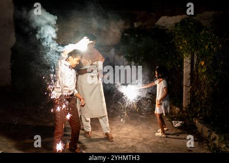 La famiglia indiana celebra Diwali con scintillanti, illuminando la notte con gioia e tradizione. Foto Stock