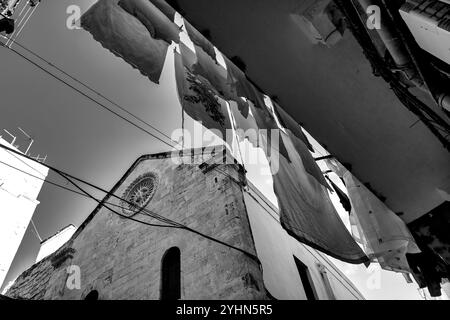 Vista in bianco e nero dal basso della facciata della chiesa di San Marco dei Veneziani a Bari, Italia, con abiti appesi al balcone, Foto Stock