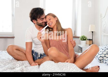 Donna incinta con partner seduto a letto. Giovane coppia che aspetta un bambino Foto Stock