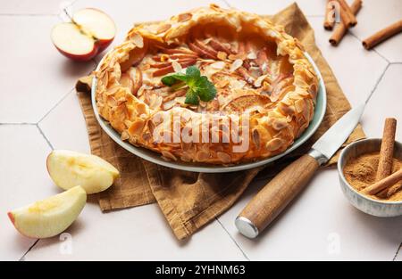 galette di mele appena sfornata decorata con fiocchi di mandorle, cannella e foglie di menta, servita su un piatto Foto Stock