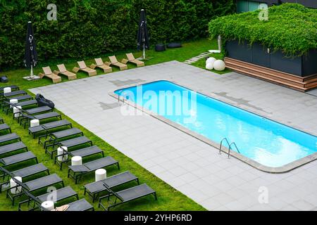 Lussuosa struttura turistica con giardino con piscina e lettini e lettini a bordo piscina Foto Stock