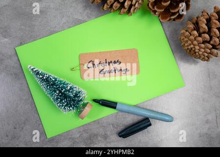 Auguri di Natale con albero di spazzolone per bottiglie, coni di pino e busta Foto Stock