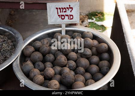 Limoni neri persiani, che sono in realtà agrumi di lime, accumulati in una ciotola d'argento in un mercato delle spezie a Tel Aviv, Israele. Foto Stock