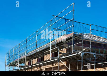 Un edificio moderno e' circondato da impalcature, che mostrano la costruzione in corso sotto un cielo limpido e soleggiato, a indicare i progressi nello sviluppo. Foto Stock