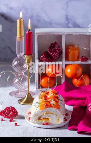 Rotolo di meringa ripieno di mascarpone, crema e marmellata di mandarini, decorato con mandarini e semi di melograno. Dessert per San Valentino, mandarino Foto Stock